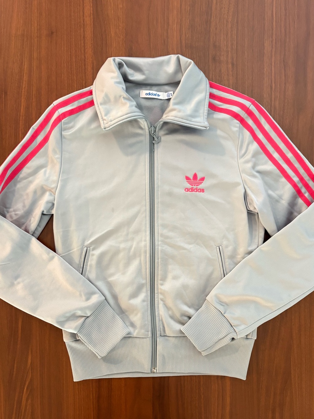 Iconic Adidas Originals zip-up track jacket in light grey with vibrant hot pink